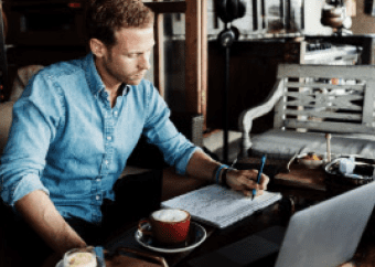Guy writing beside a cup of coffee